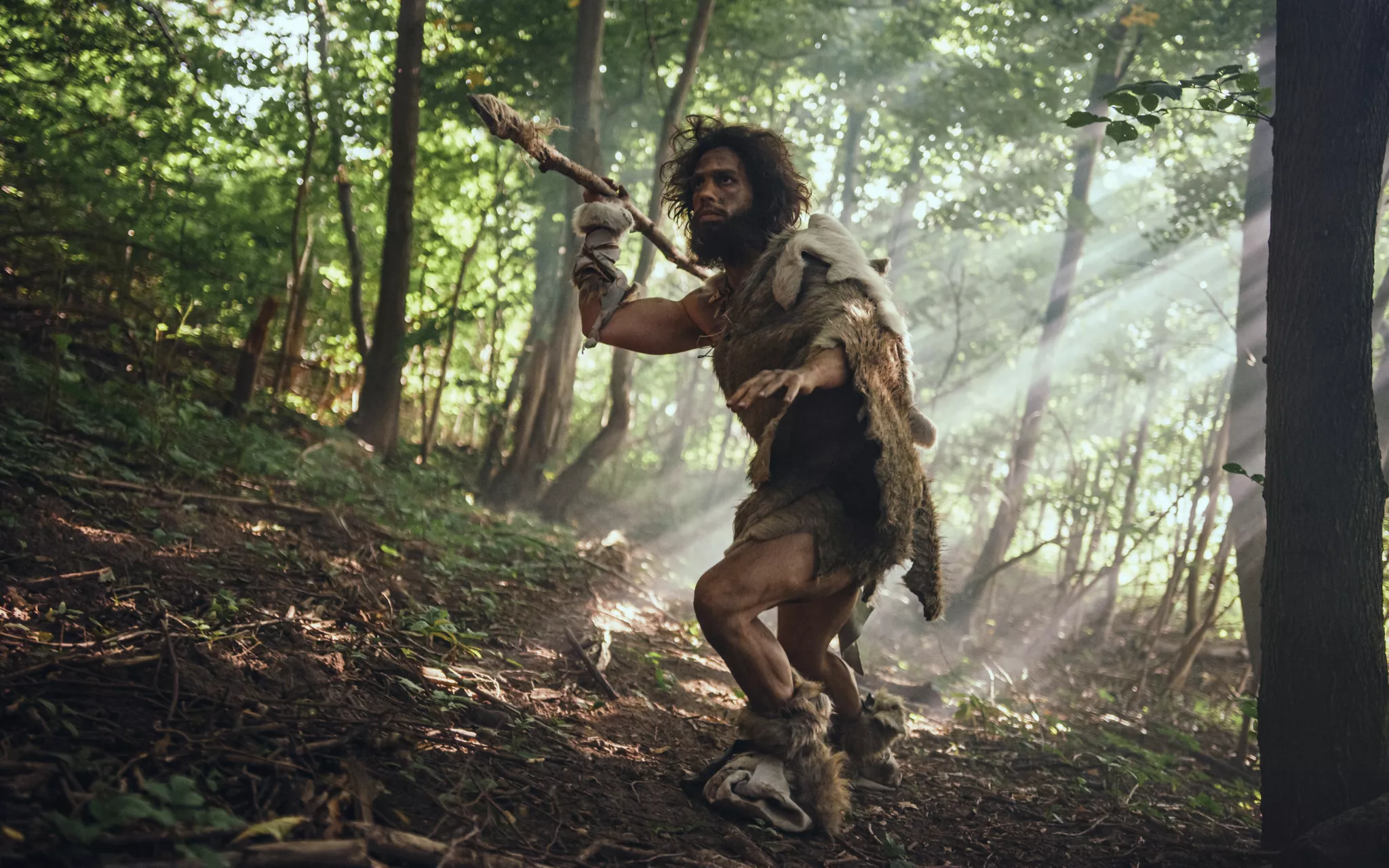 Homme préhistorique avec une lance dans une forêt